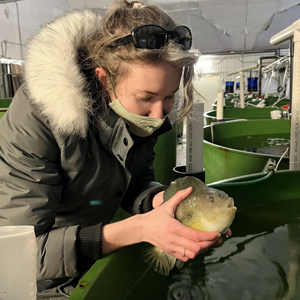 Arts and Science student holding a fish on their co-op work term 