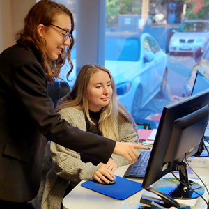 Business student with co-worker looking at their computer screen.