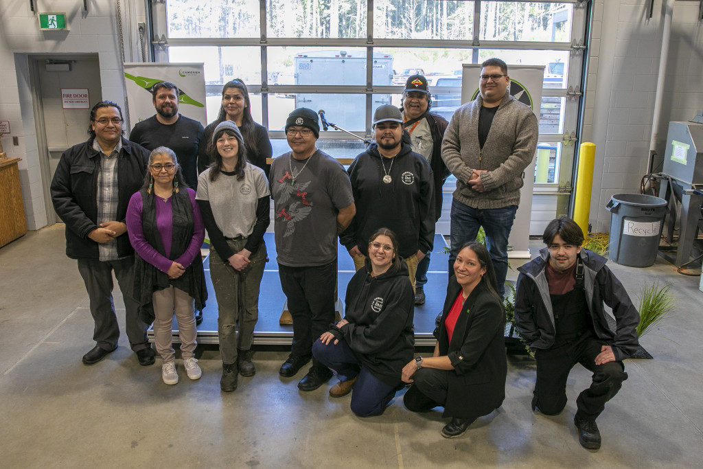 A group of people gathered in trades education room look at the camera