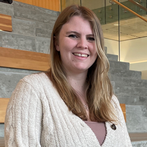 A young women sits on a the steps of the learning commons.