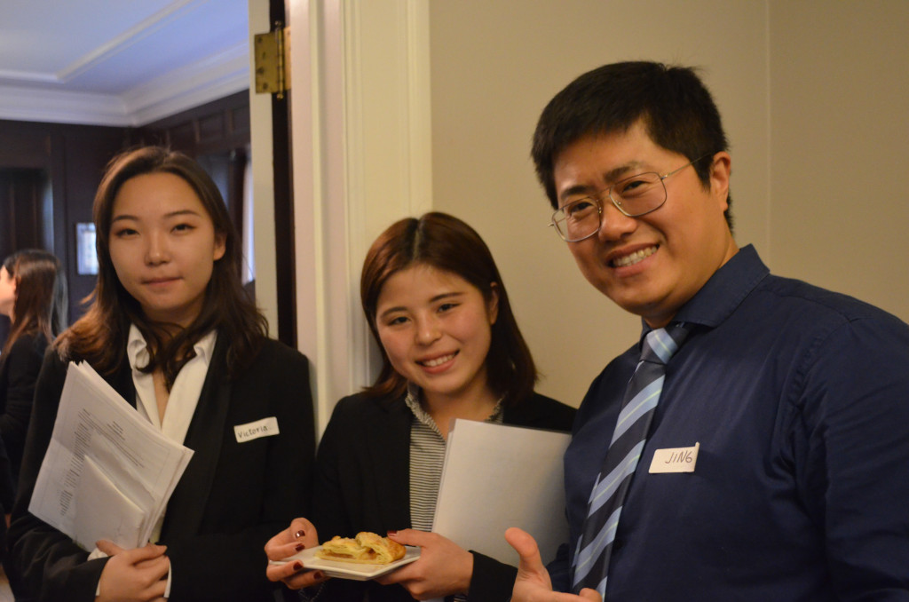 Two female students and one male student in business clothes smile and face the camera