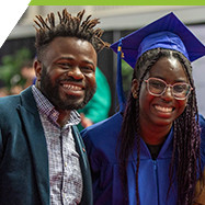 Graduate in cap and gown and their supporter smiling at Convocation