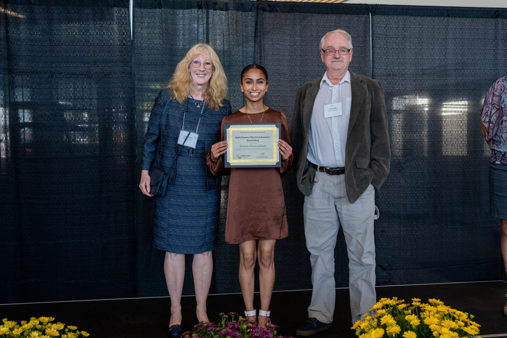 Female holding award with group of three people.