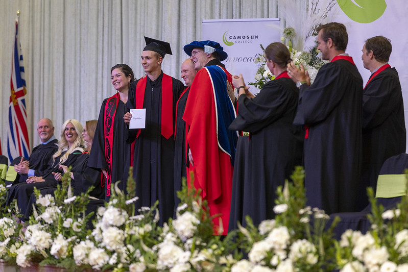 Convocation ceremony with grads crossing the stage and being congratuled by faculty 