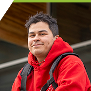 Jason sitting and smiling in front of the CTEI building in the Interurban Campus.