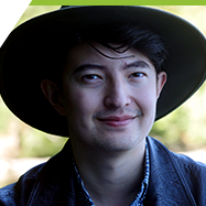 Max, a Peer Pod facilitator, in a hat and jacket in front of a lake.