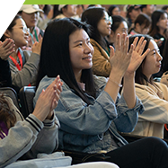 1. A diverse group of people in a conference room, with hands raised, indicating enthusiasm or seeking to contribute to the discussion.