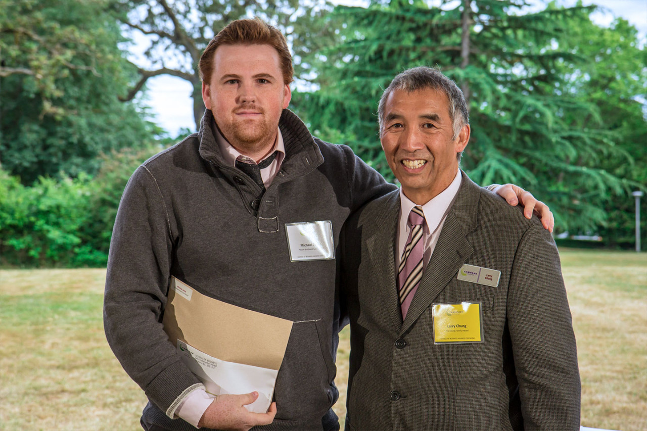 A student poses with a faculty member showing off his award