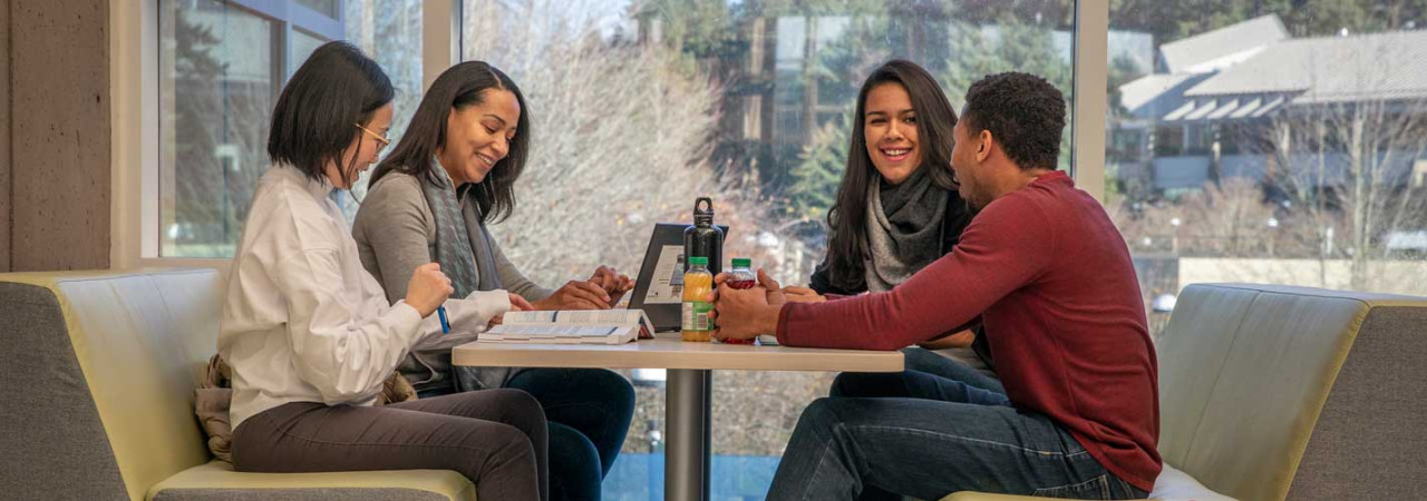 4 people sitting at table talking and working