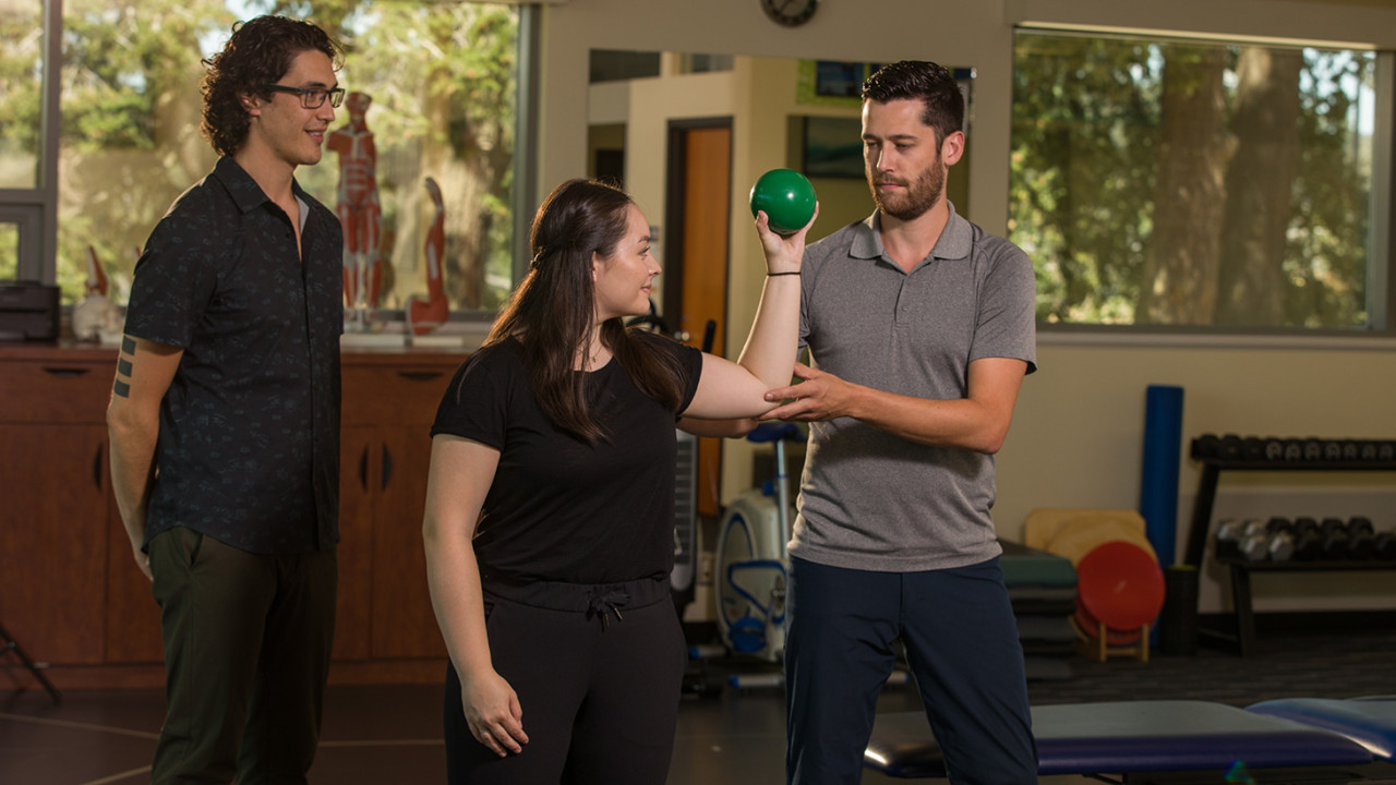 A student looks on as an athletic therapist does a demonstration on another student