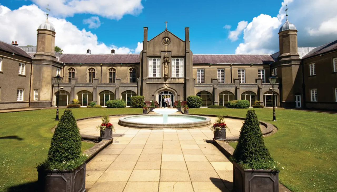 A historic looking building with a large fountain in front.