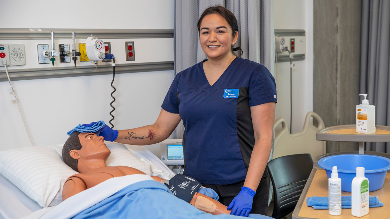 A health care assistant student working on a medical practice mannequins.