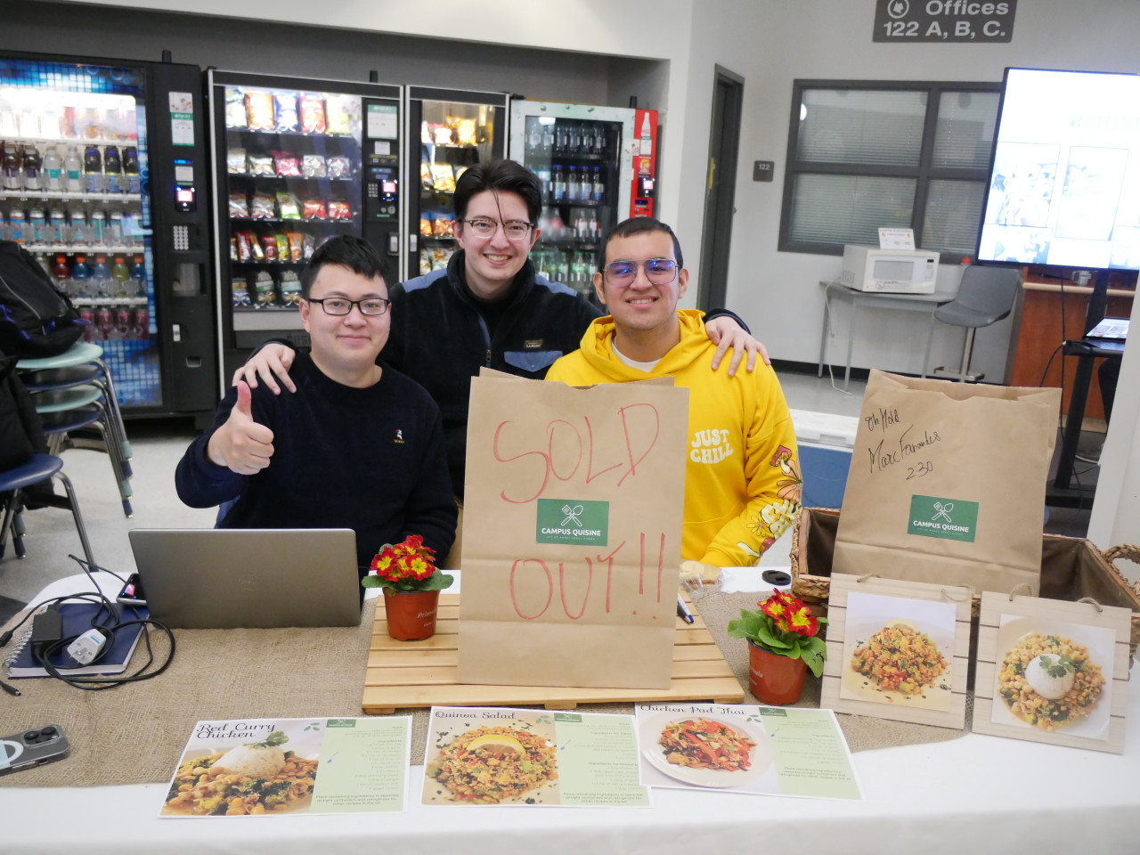 Three people gather around a meal kit bag at a table.
