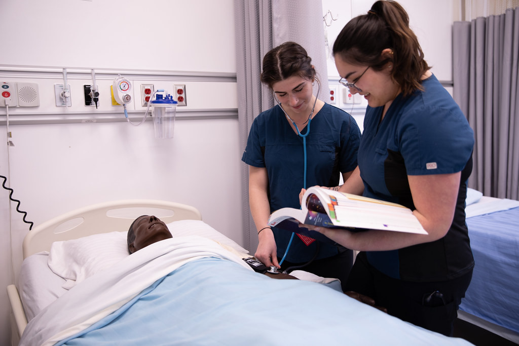 Two student nurses reading textbook