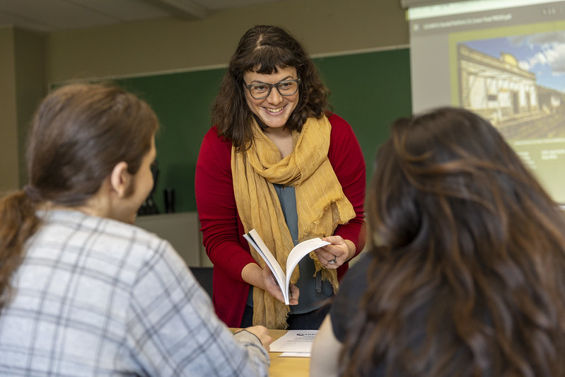  A college instructor leads a classroom discussion, surrounded by eager students ready to learn.