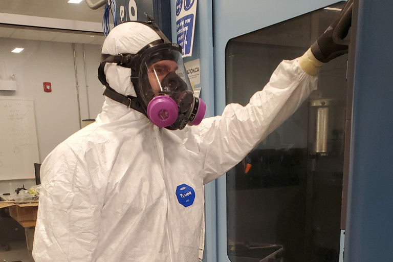 Man wearing white industrial coveralls while working. 