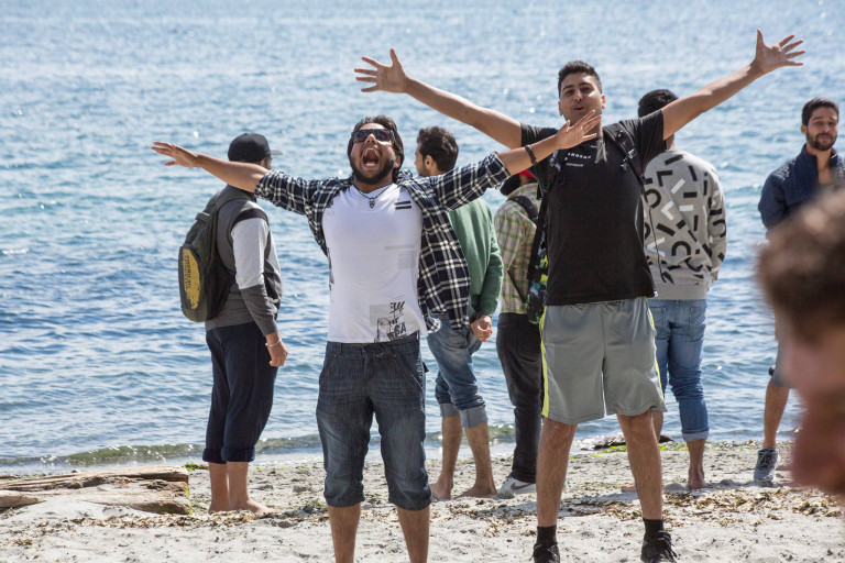 Students with their arms flung out enjoying a day of sunshine at the beach.