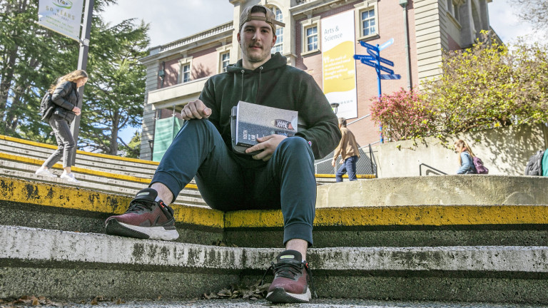 A man sitting on steps, holding a book.