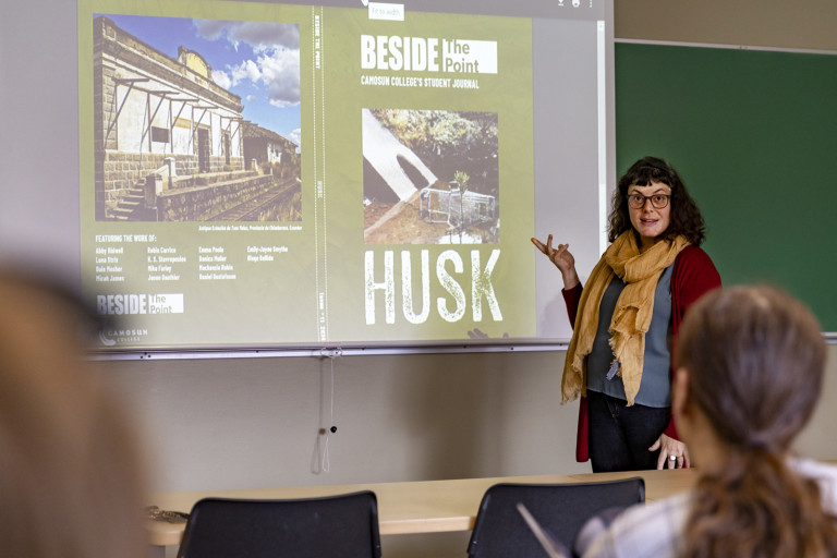 A woman confidently presents to a classroom full of engaged students, sharing her knowledge and insights.